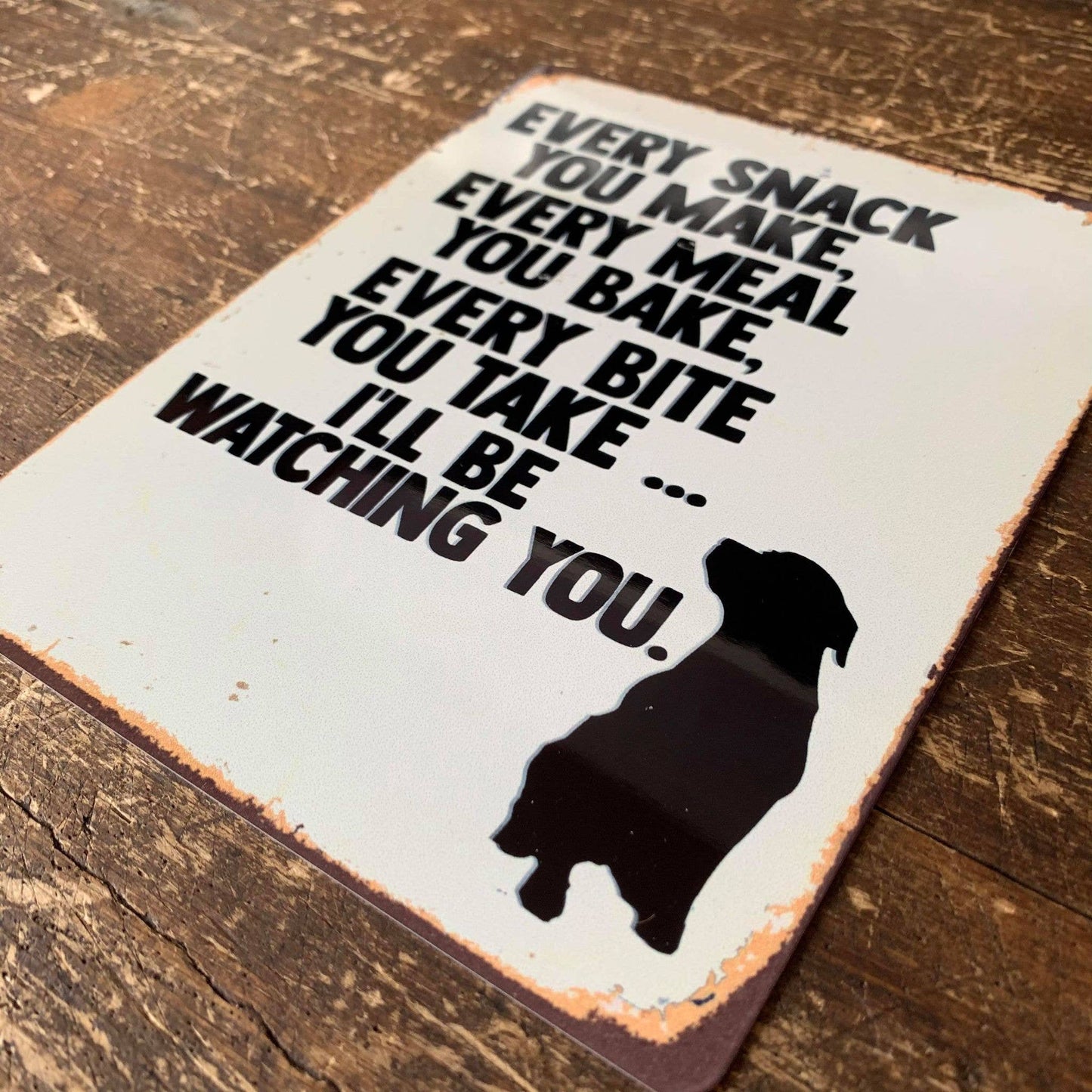 Decorative sign with a dog silhouette and text on a wooden surface