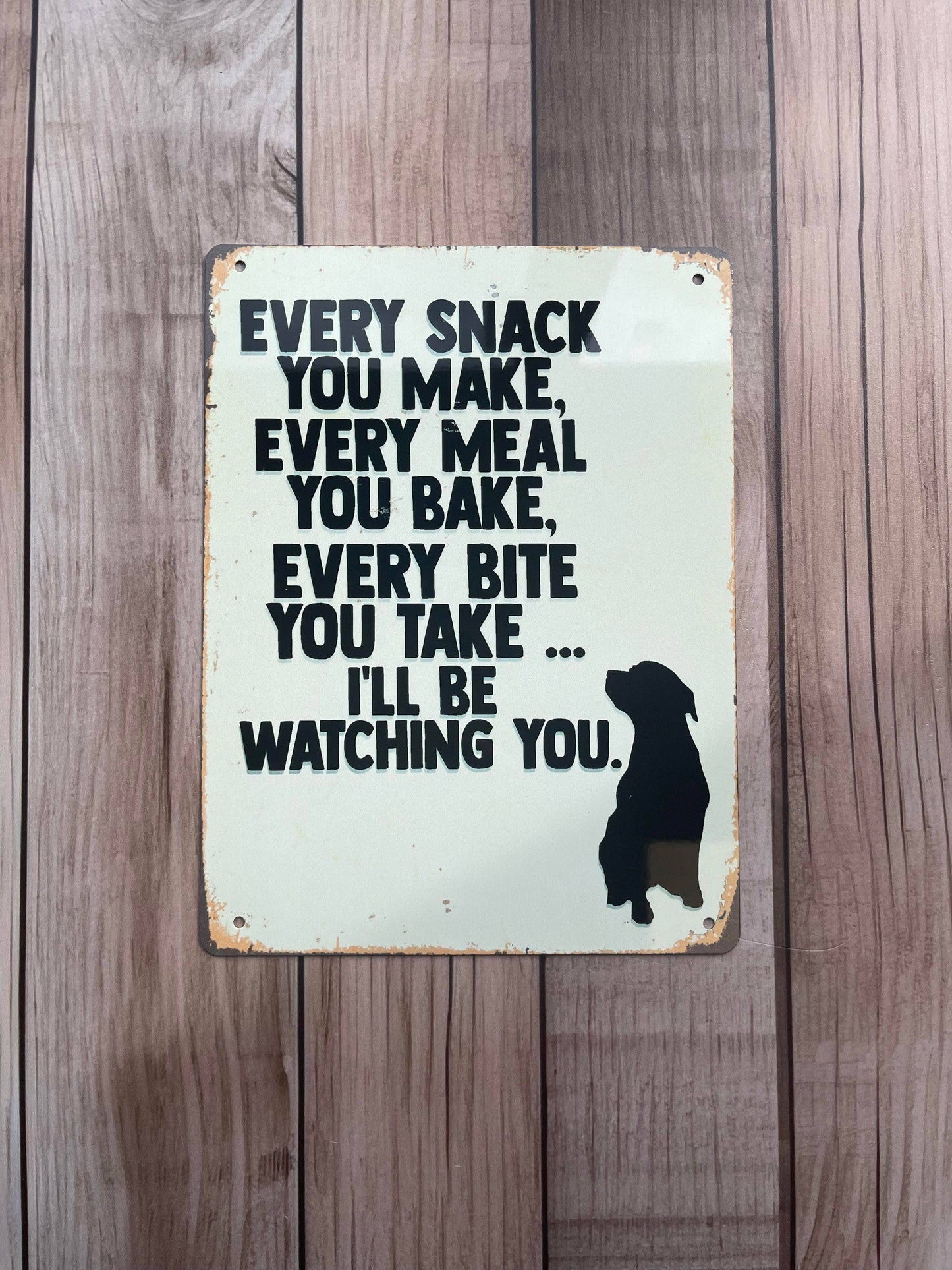 Metal sign with a dog silhouette and text on a wooden background