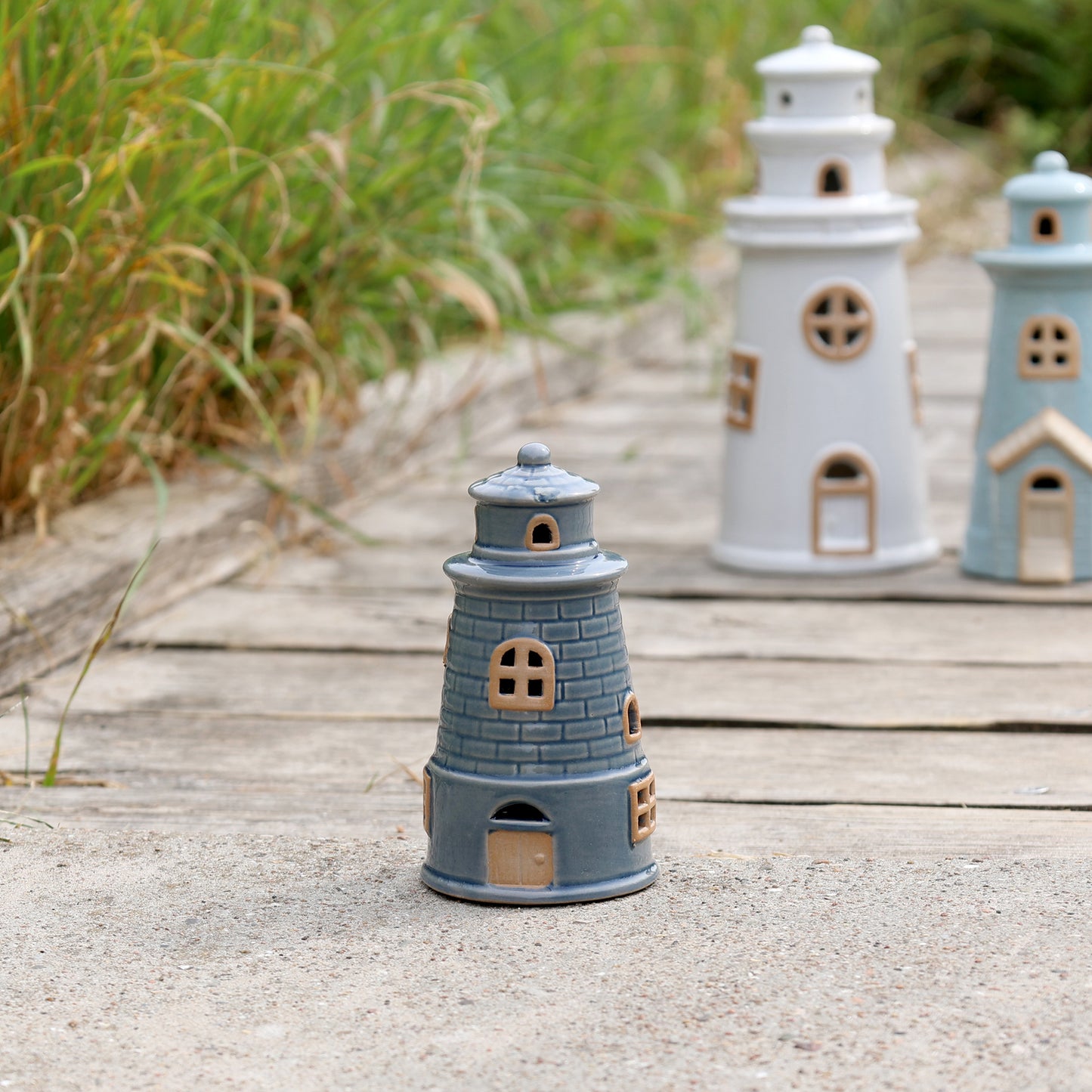 Decorative lighthouse models on a wooden surface with grass in the background