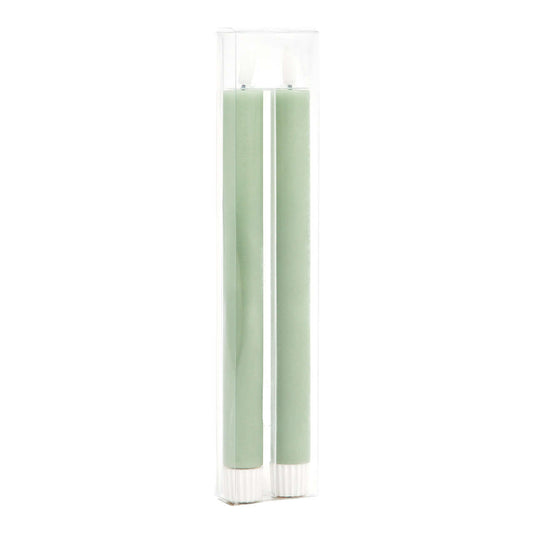 Two green candles in a clear glass holder on a white background