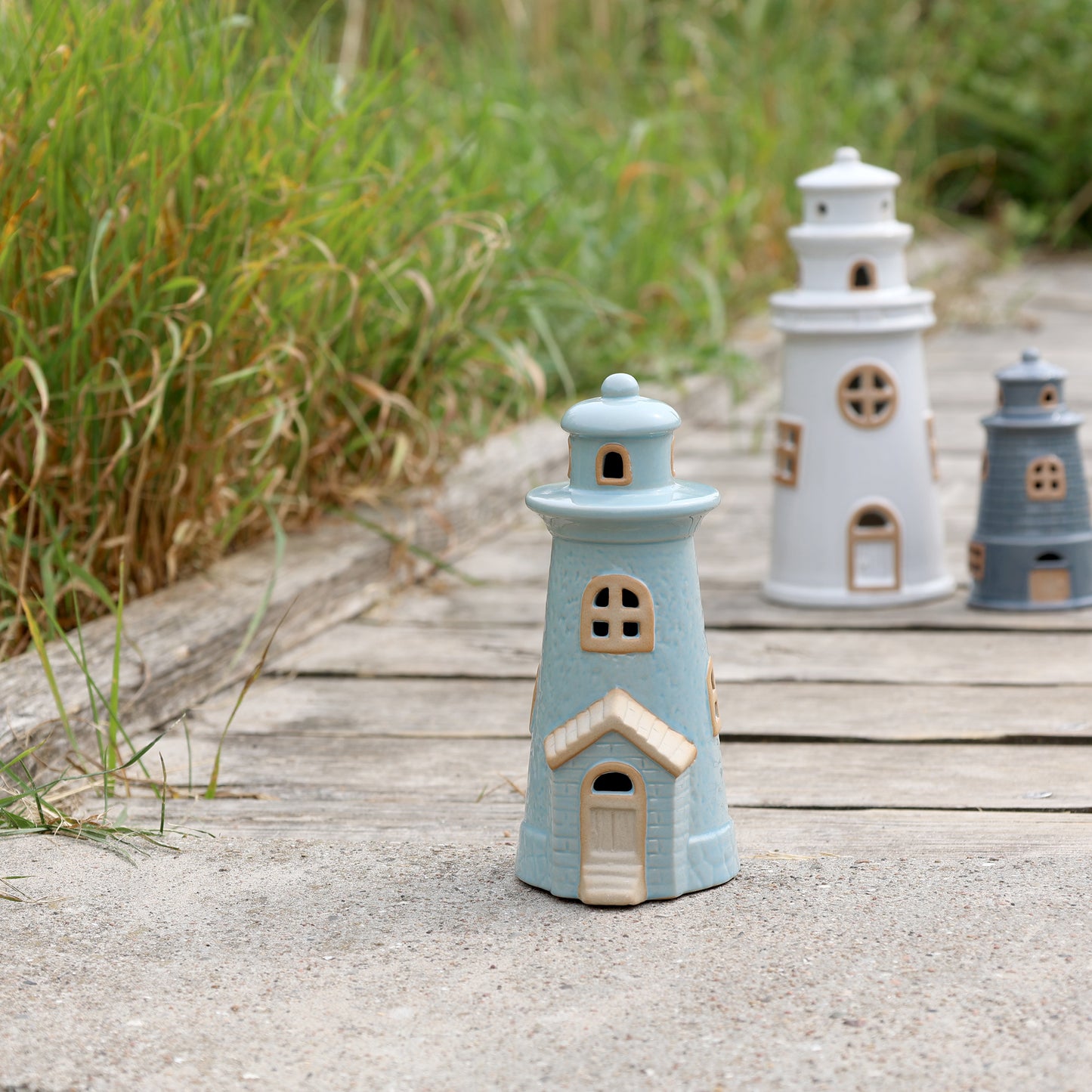 Decorative lighthouse figurines on a wooden surface with grass in the background
