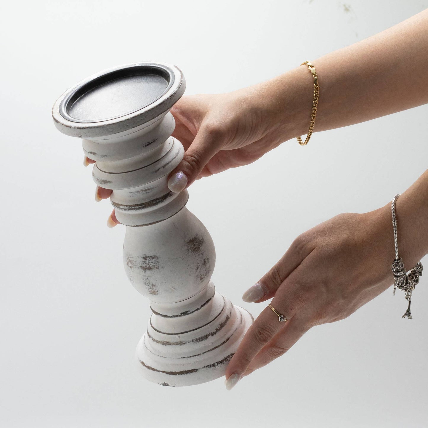 Person holding a white ceramic candle holder with a black top on a light background