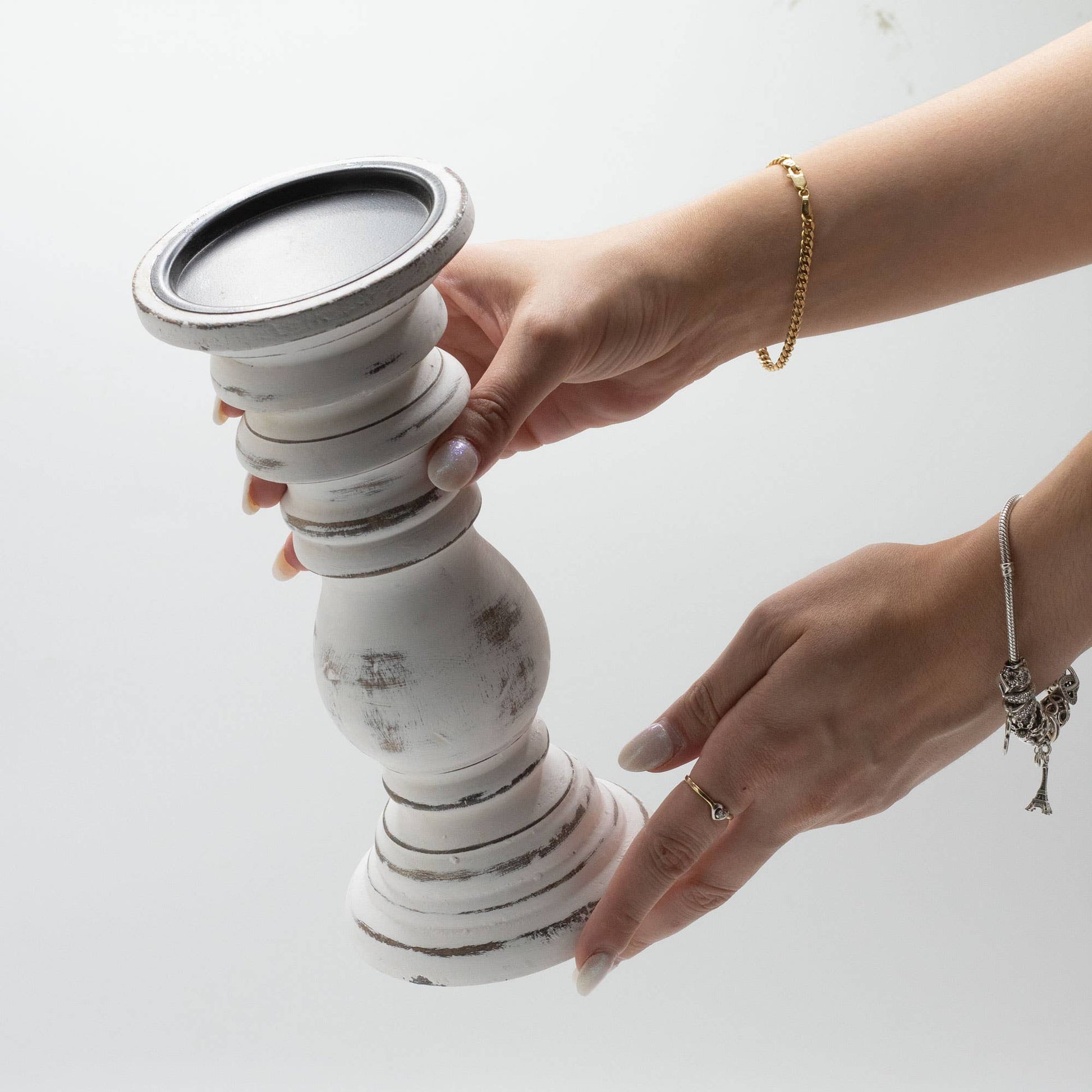 Person holding a white ceramic candle holder with a black top on a light background