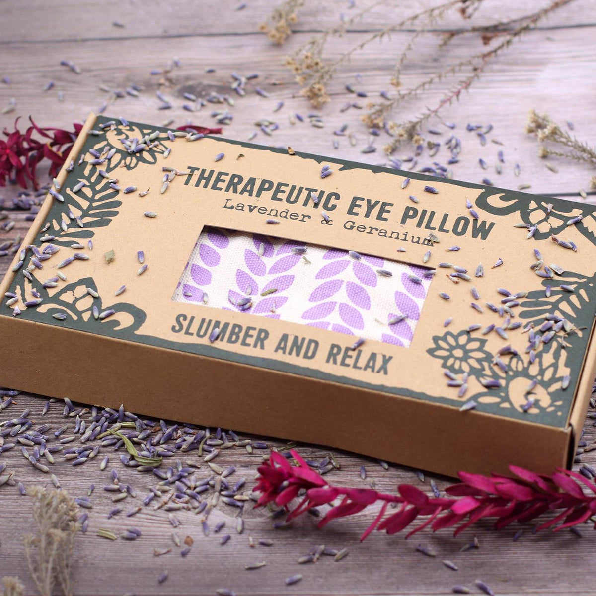 Therapeutic eye pillow packaging with lavender and geranium on a wooden surface.