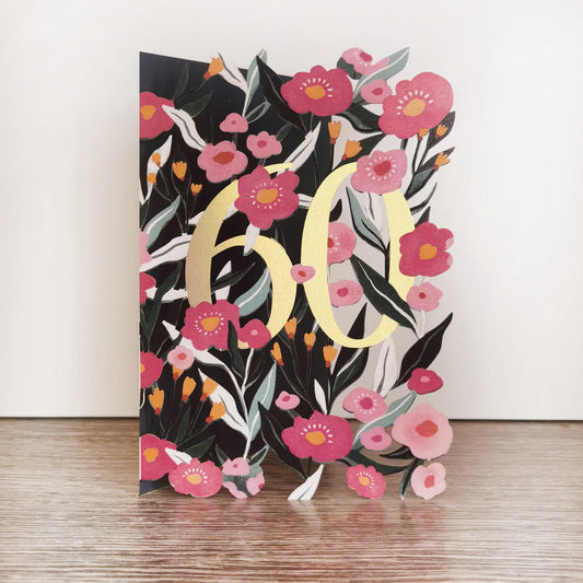 Decorative paper with floral design and large 'LOVE' letters on a wooden surface.