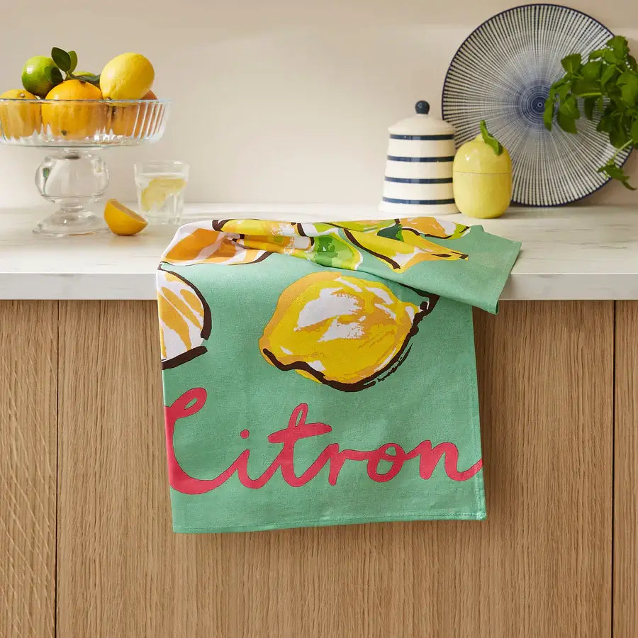 Kitchen towel with lemon design and 'Citron' text hanging on a wooden cabinet.