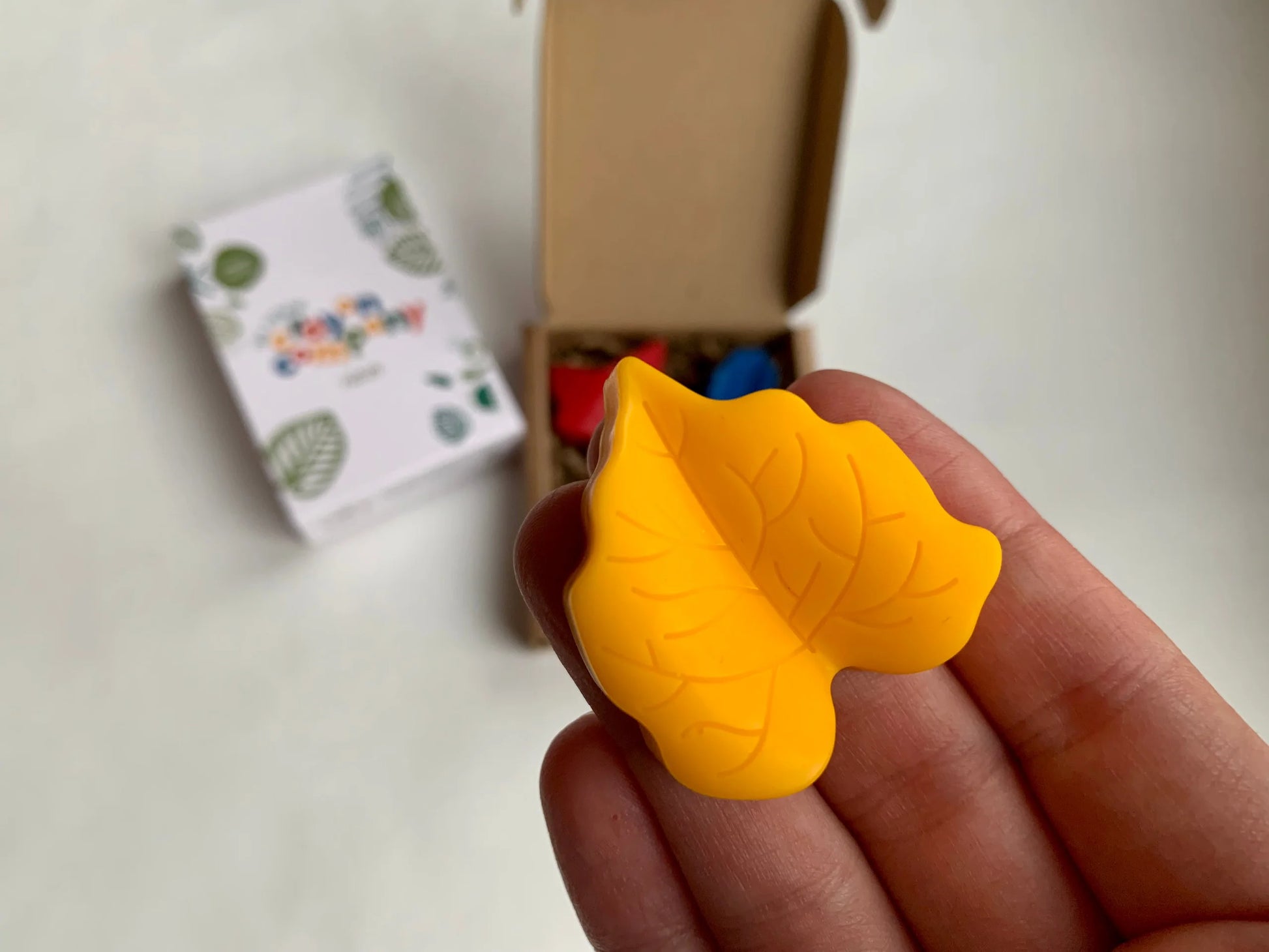 Yellow leaf-shaped crayon held in a hand with a blurred background