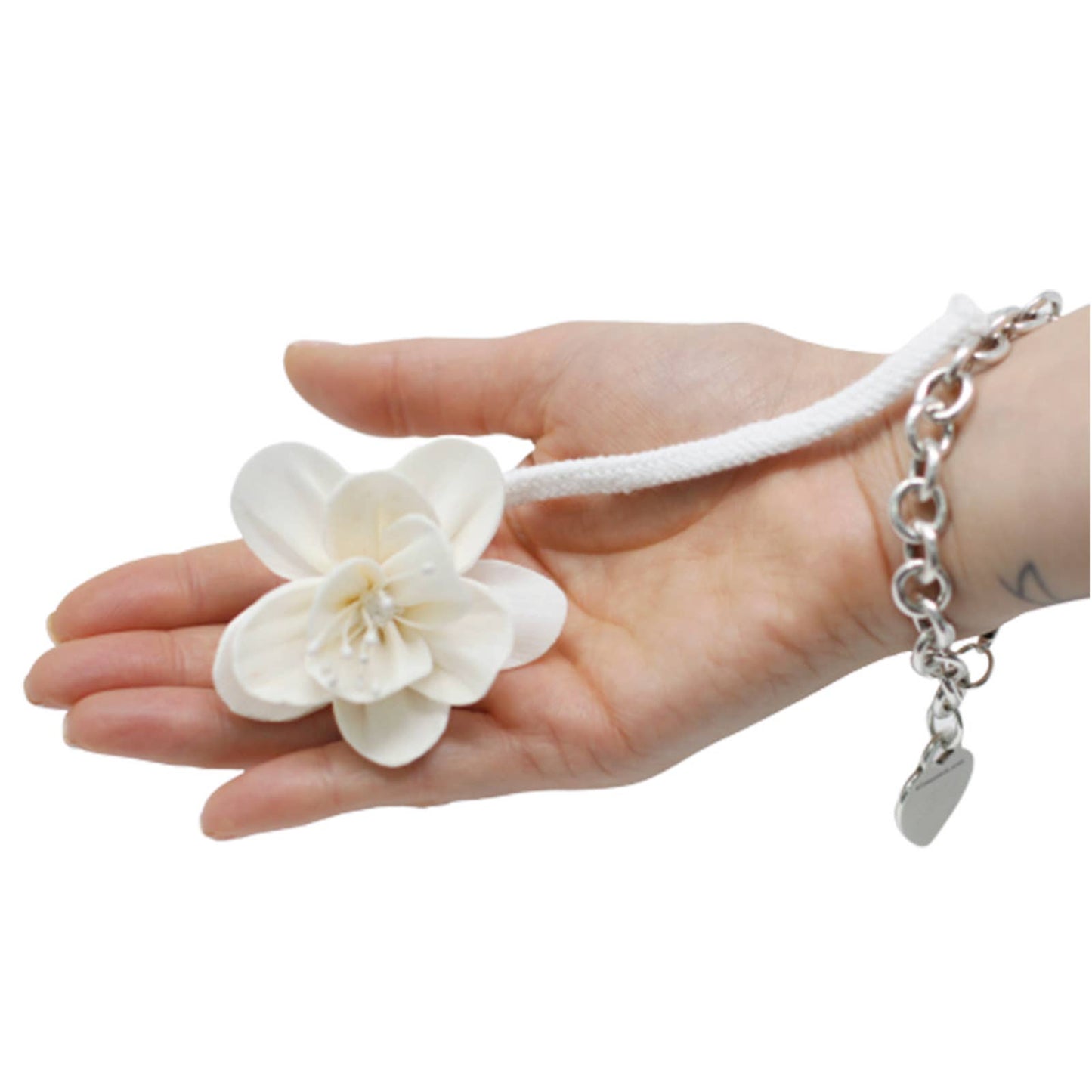 Hand holding a white floral accessory with a chain on a white background