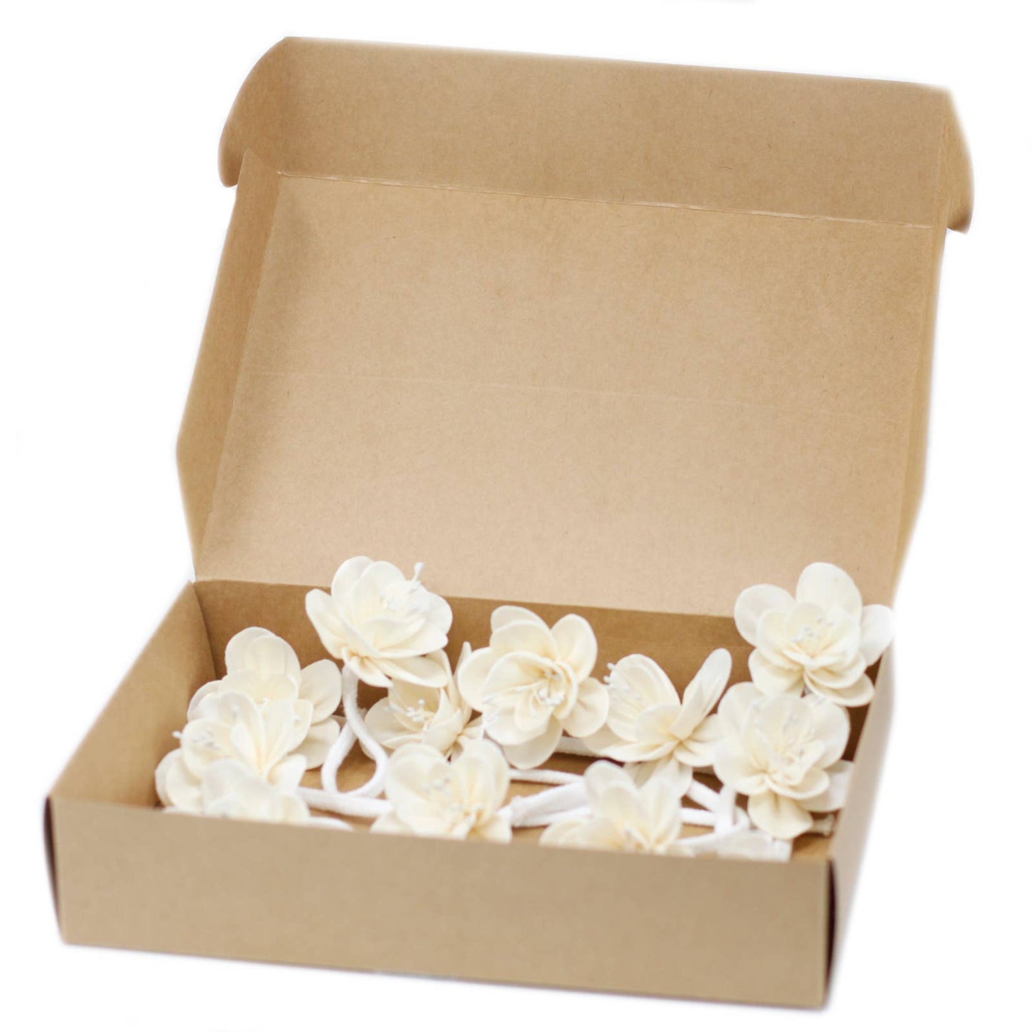 Open cardboard box containing white floral diffuser accessory on a white background