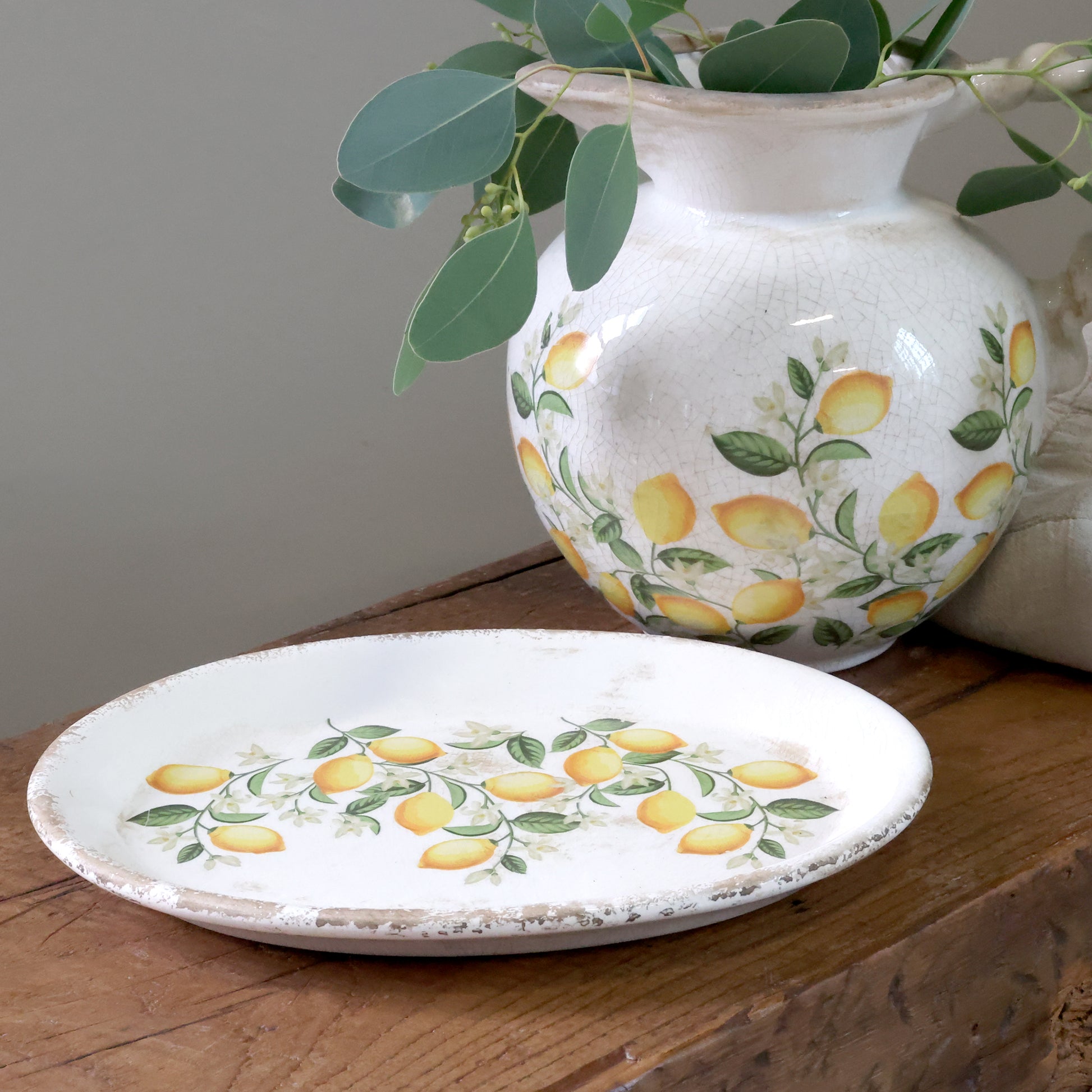 Ceramic vase and plate with lemon design on a wooden surface