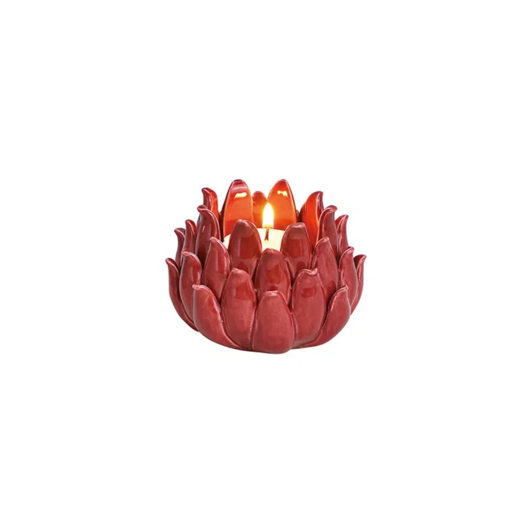 Red lotus-shaped candle holder with a lit candle on a white background