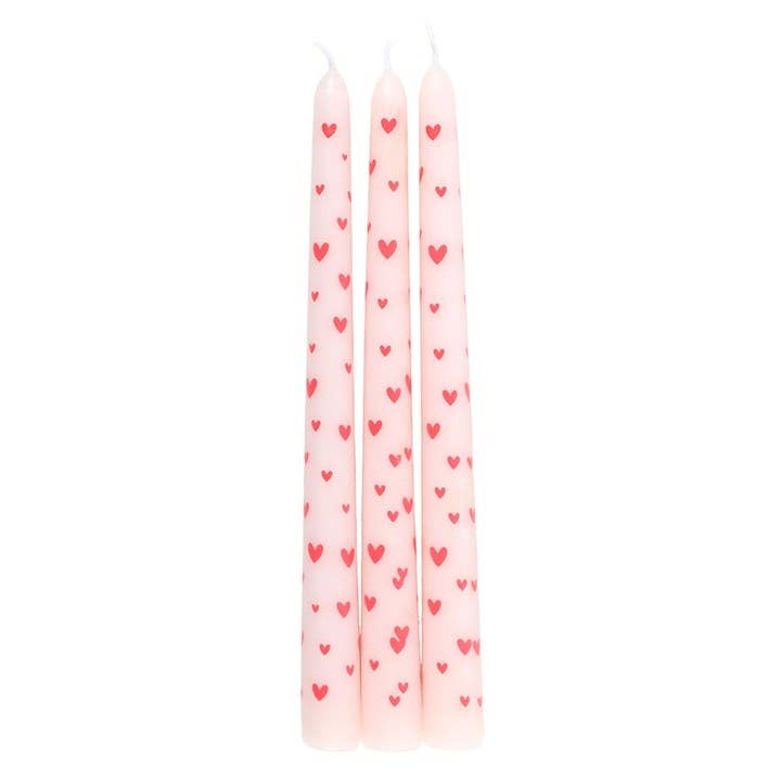 Set of three pink candles with red heart patterns on a white background