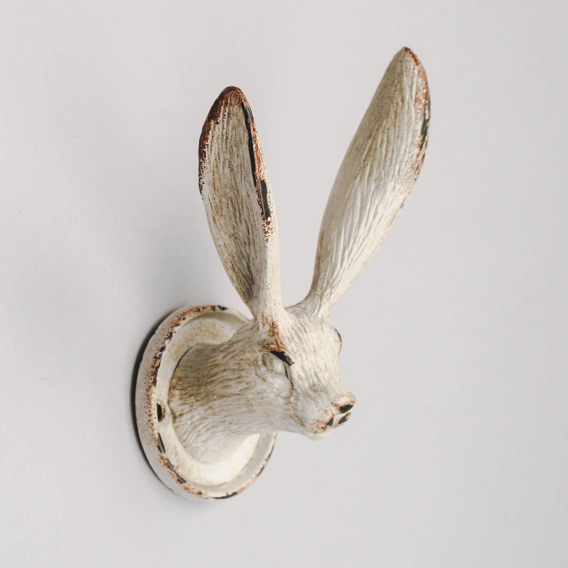 A metal wall hook in the shape of a march hare with a beige and brown finish.