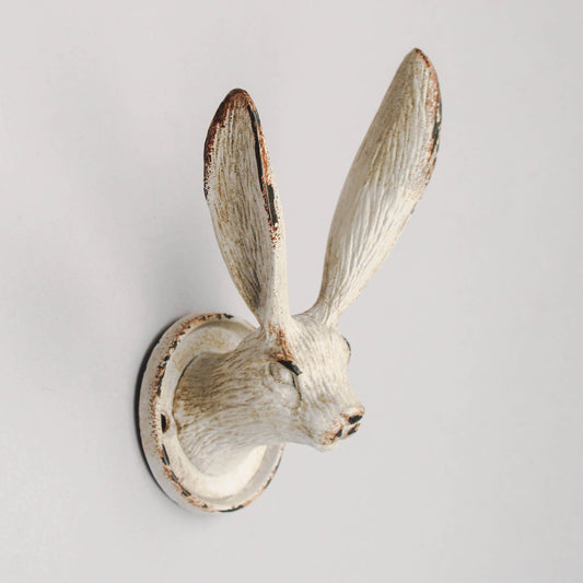 A metal wall hook in the shape of a march hare with a beige and brown finish.