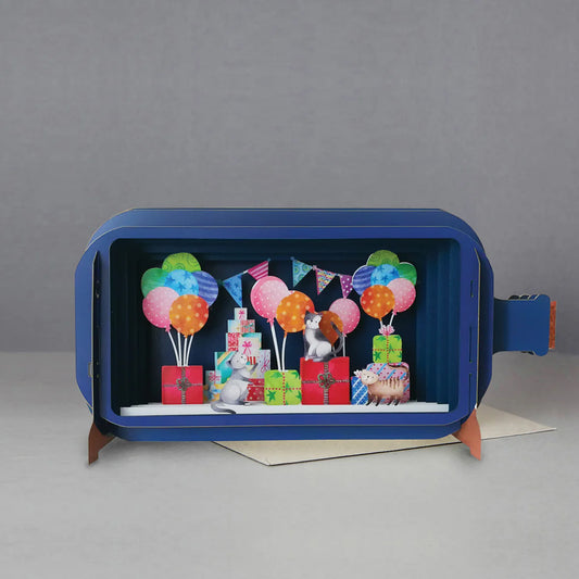 A pop up card in the shape of a bottle with a colourful scene of cats with party balloons and presents