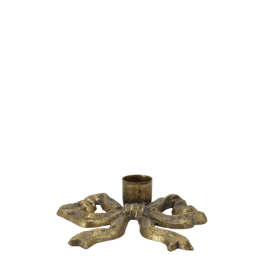 A distressed brass bow-shaped candle holder with a central cup, set against a plain white background.