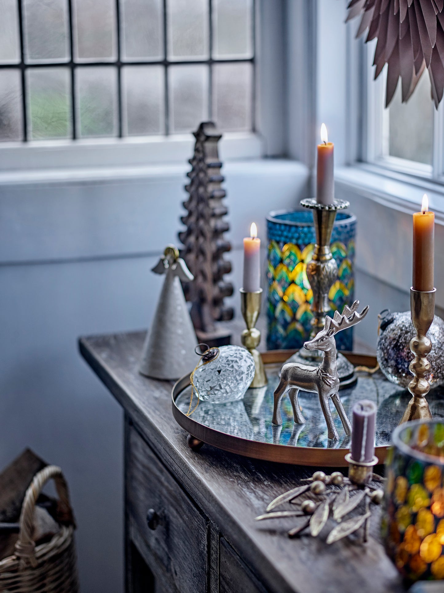 Decorative items on a wooden surface with candles and a window in the background