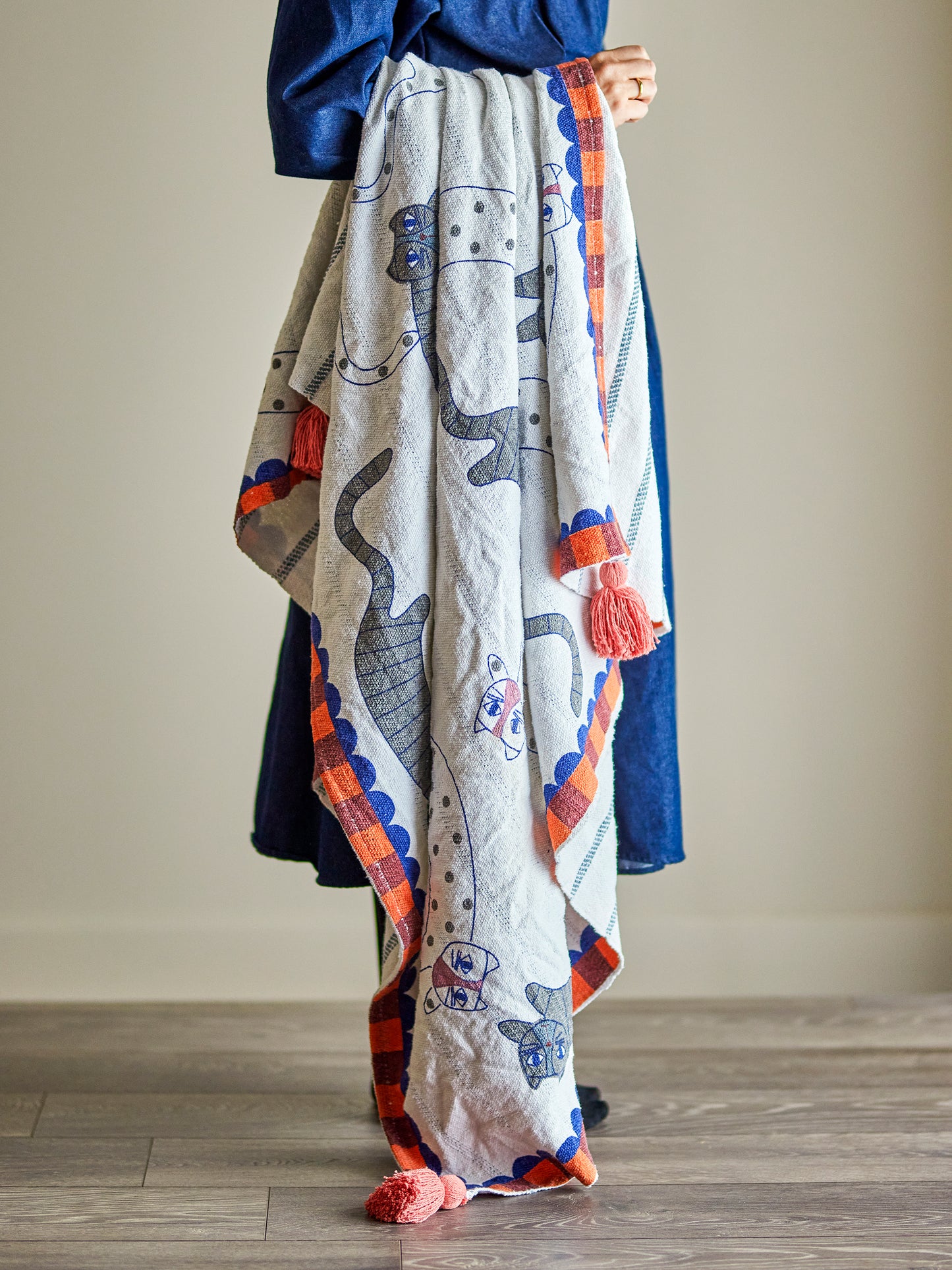 Person holding a colorful blanket with cartoon designs on a plain background