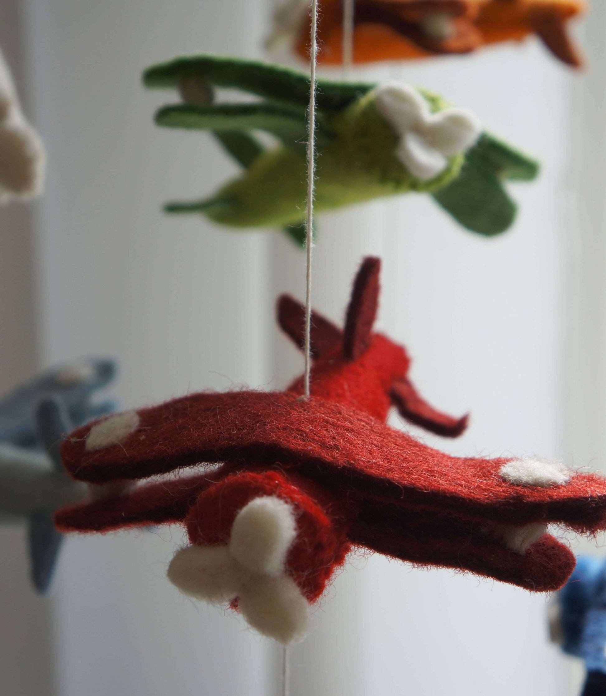 Handmade mobile featuring colorful airplane-shaped plush toys with clouds, hanging from a wooden ring.