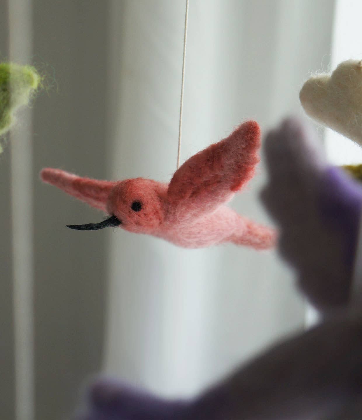 Pink felted bird toy against a blurred background