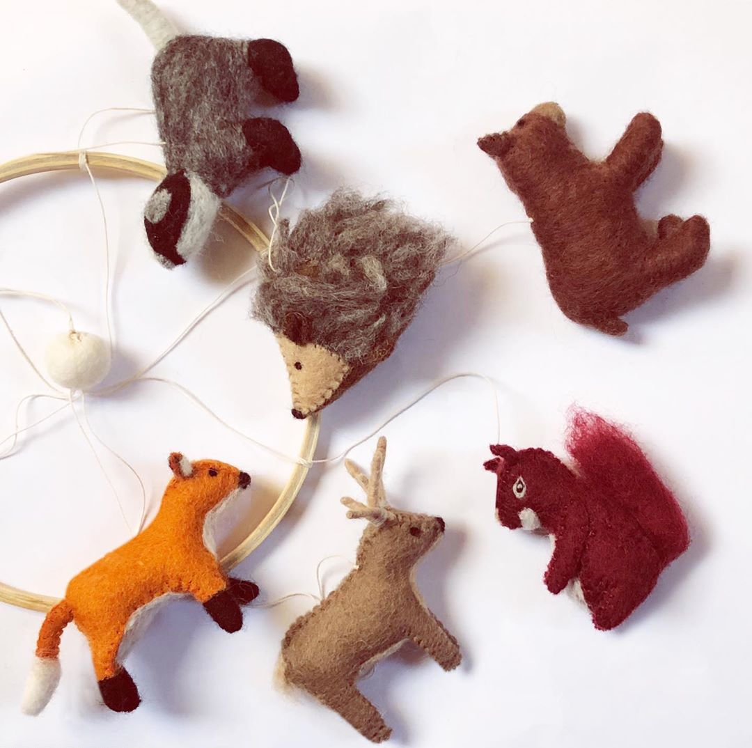Set of felt animal ornaments including a fox, deer, hedgehog, bear, and squirrel on a white background.