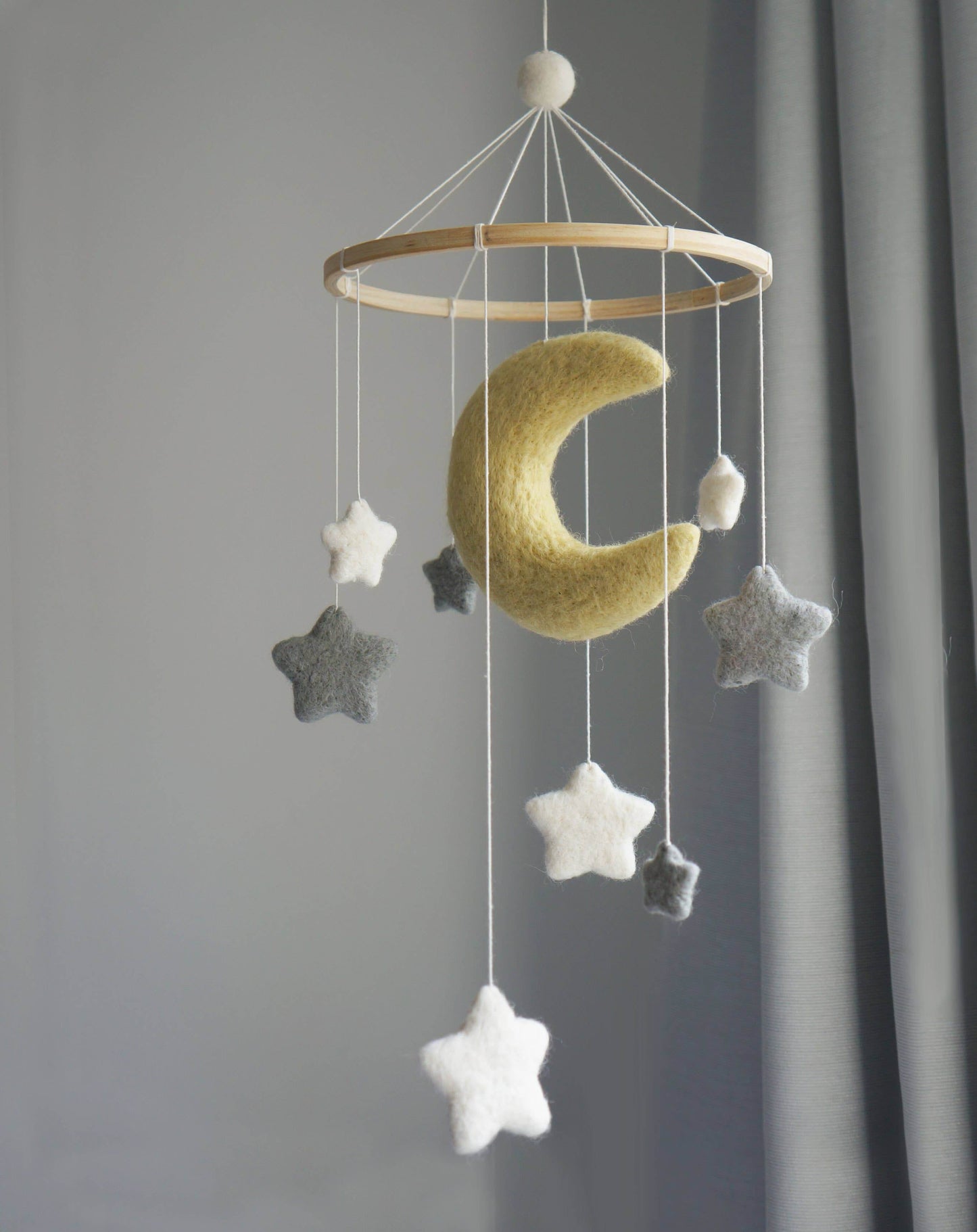 A decorative mobile featuring a yellow crescent moon with stars hanging against a neutral background.