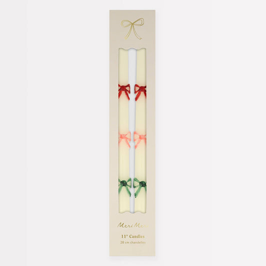Two candles with decorative bows in a beige packaging on a white background