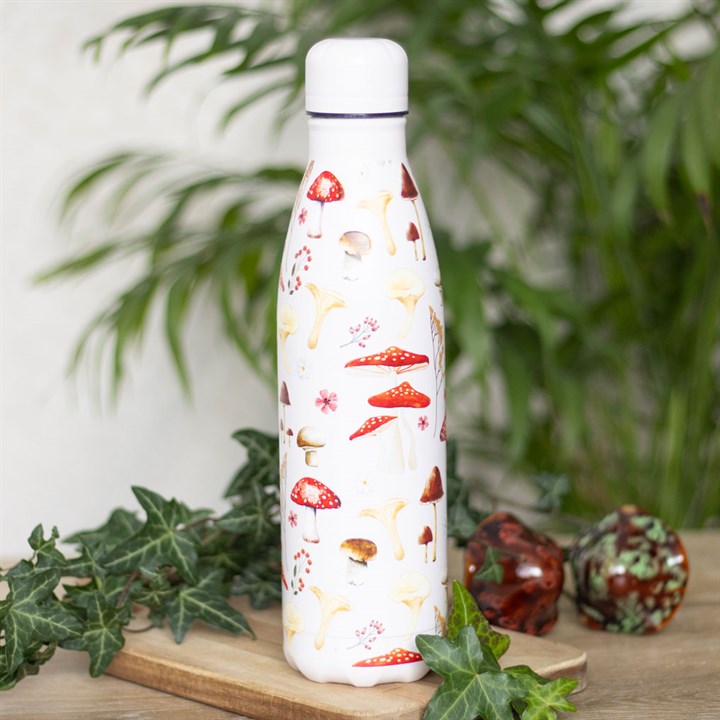 White water bottle with mushroom design on a wooden surface with greenery in the background
