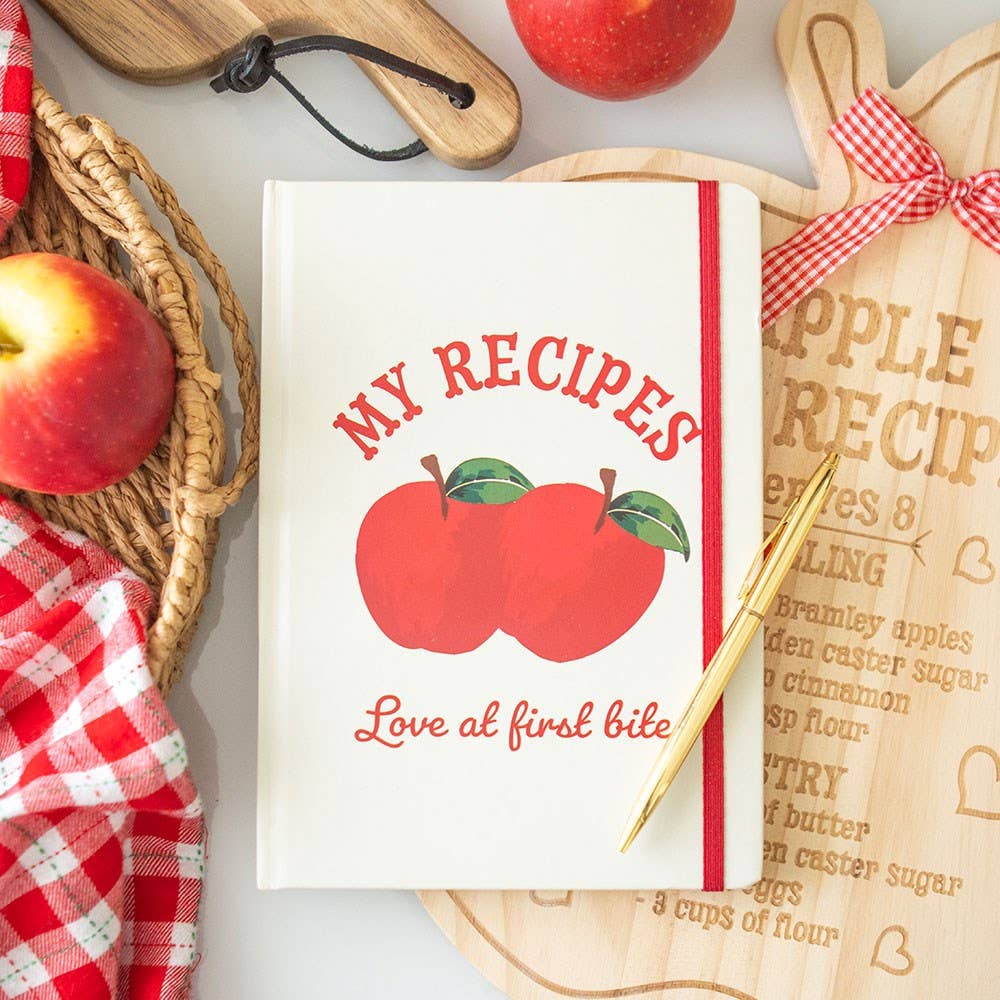 Cookbook titled 'My Recipes' with apples and kitchen items on a table