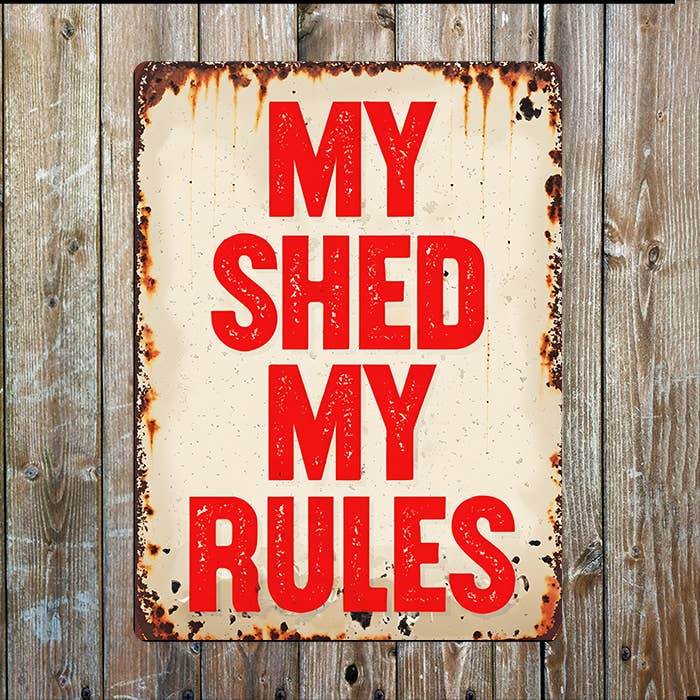 Rustic metal sign with 'My Shed My Rules' text on a wooden background