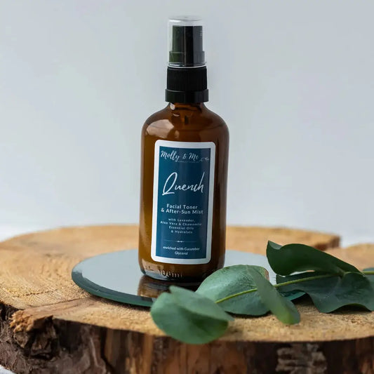 Brown spray bottle labeled 'Quench' on a wooden surface with green leaves.