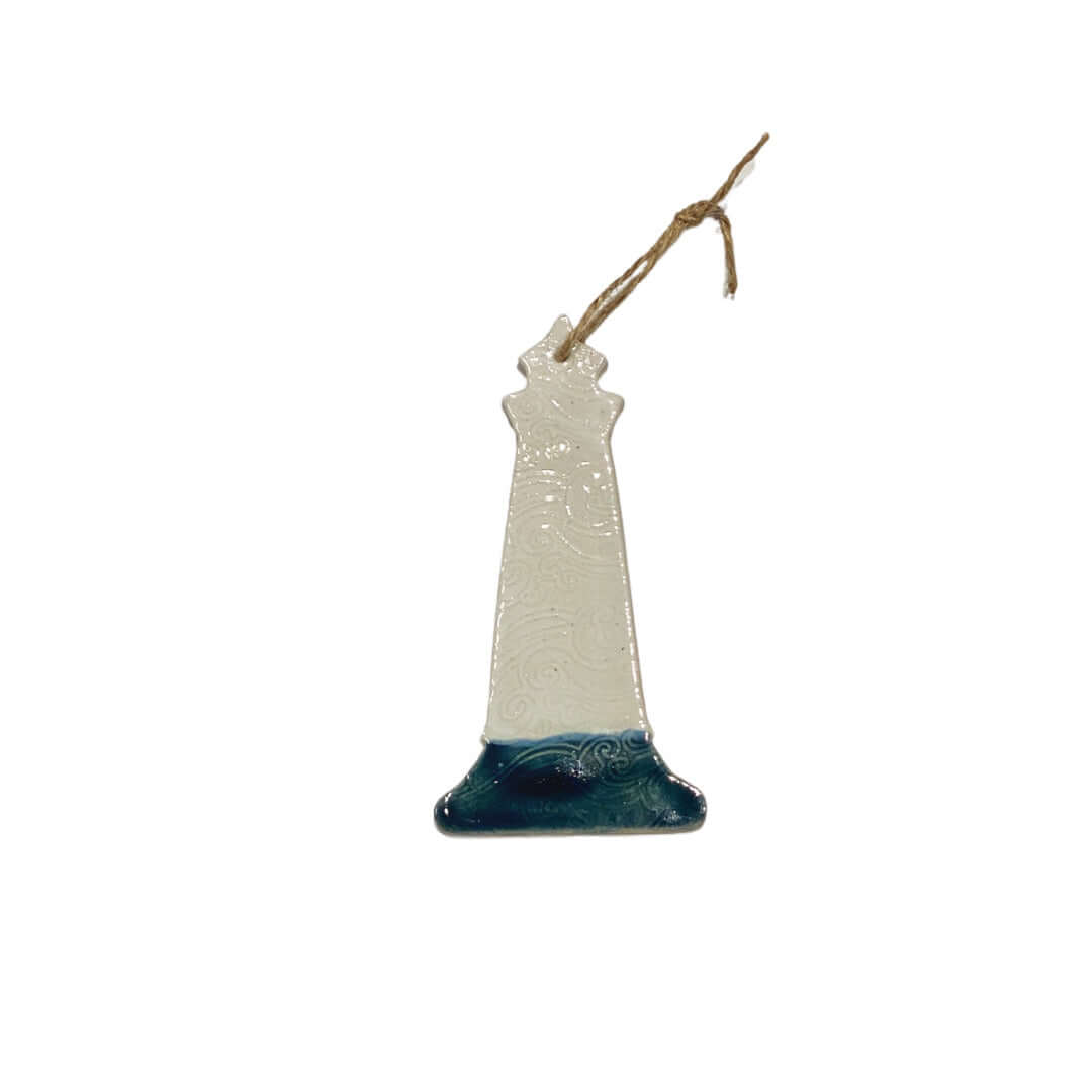 A ceramic lighthouse decoration with a white body, red base, and grey accents, hanging from a jute string.