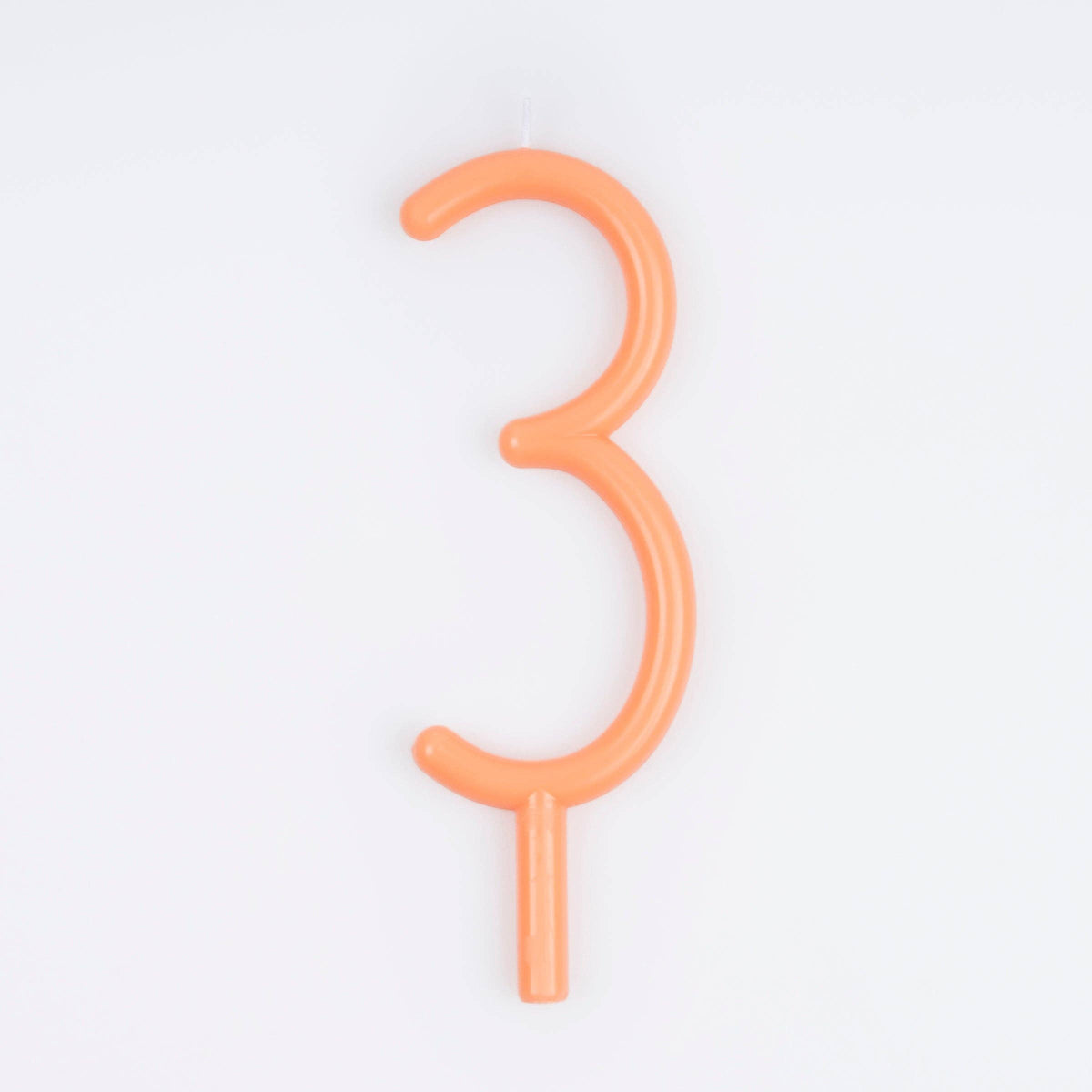 An orange wax number 3 birthday candle on a white background.
