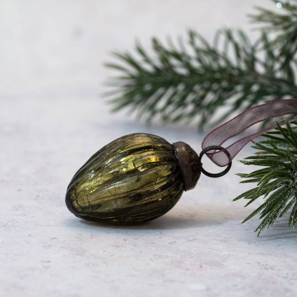 Green glass ornament on a branch with snow in the background