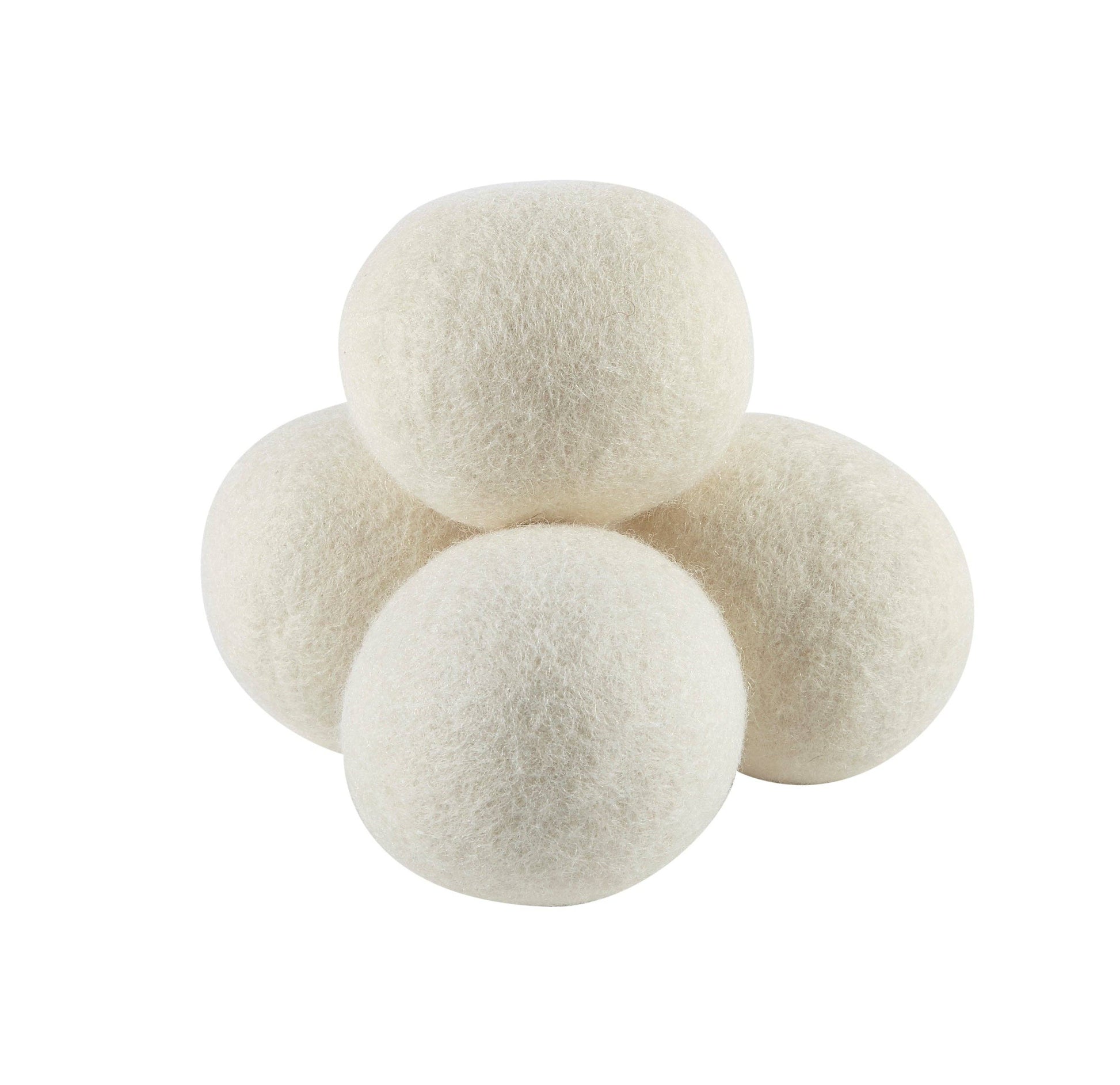Four white wool dryer balls on a white background
