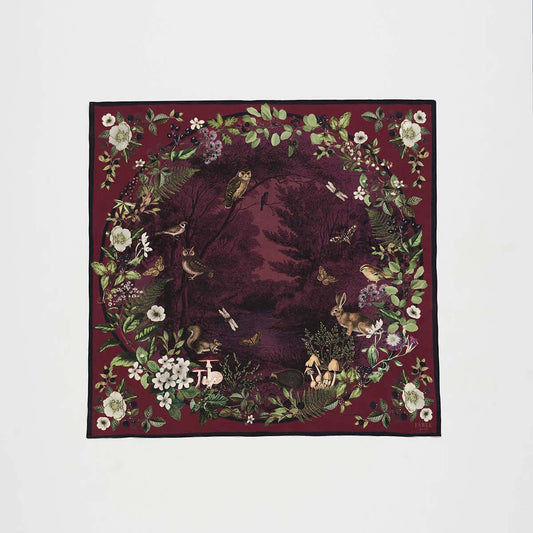 A square scarf featuring a detailed woodland garden illustration with a dark burgundy background, surrounded by a border of white flowers, green leaves, and small birds.