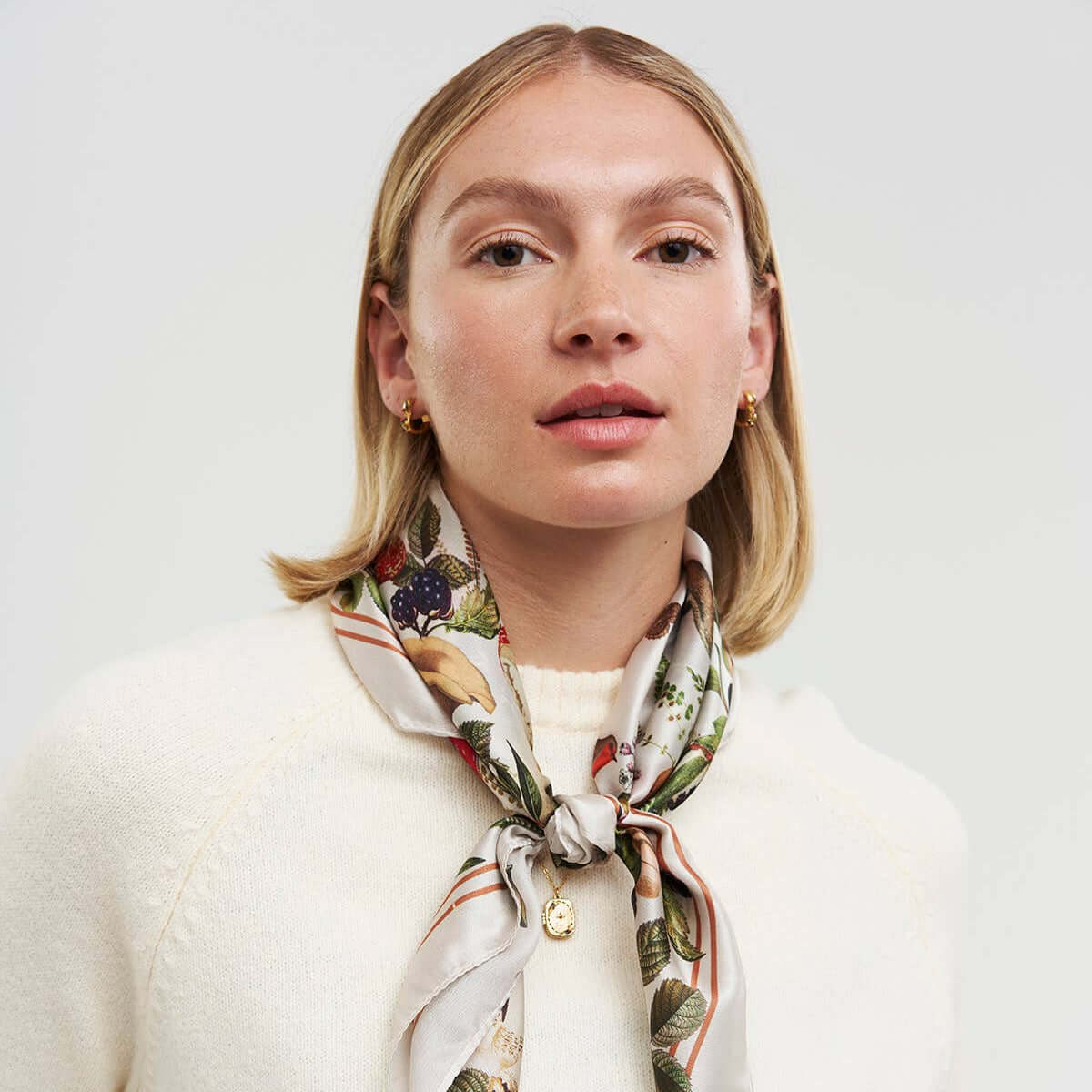 Woman wearing a floral scarf on a plain background