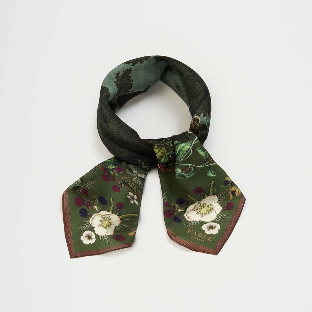 A small square scarf with a dark green and black floral print, tied in a loop to display its shape and pattern, set against a plain light gray background.