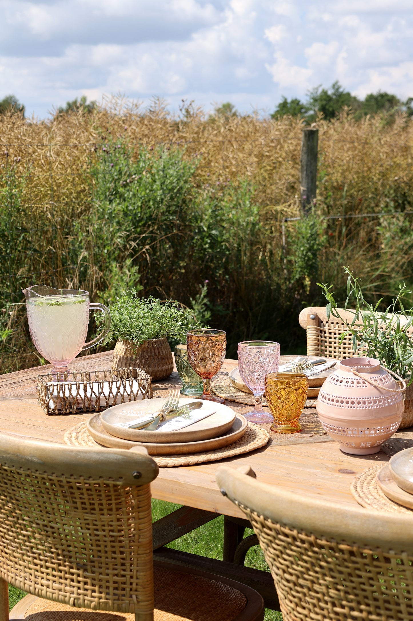 Outdoor dining setup with a table, chairs, and decorative items in a natural setting.