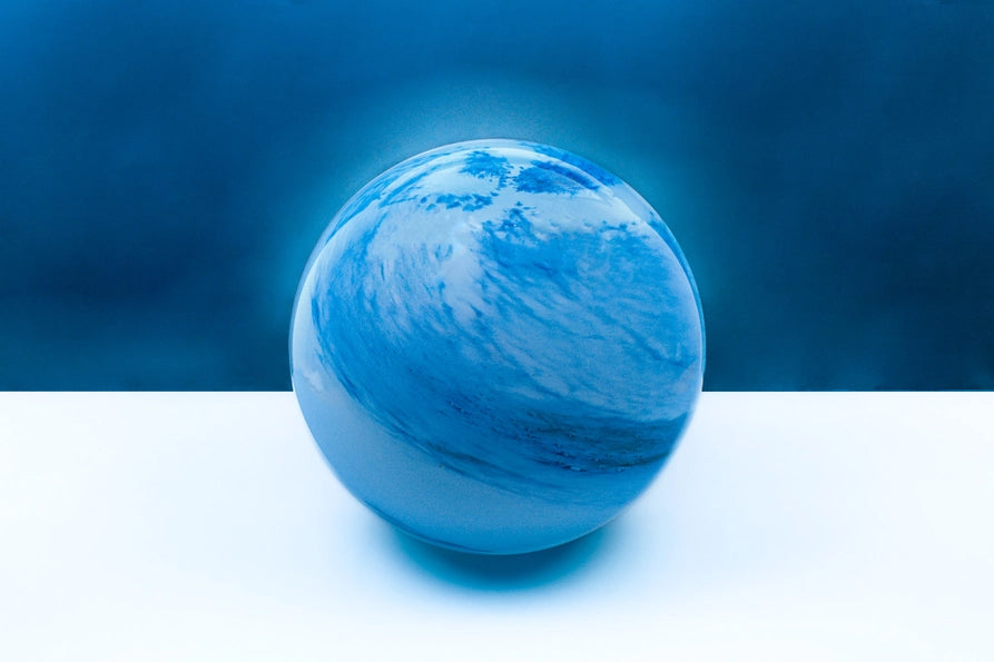 Blue glass sphere lamp on a white surface with a blue background
