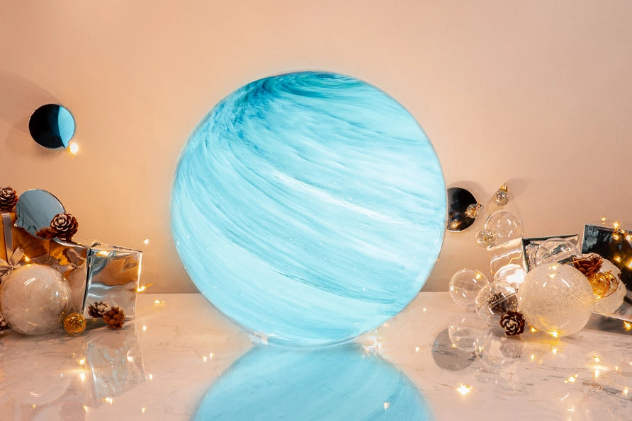 Blue spherical lamp on a reflective surface with decorative items in the background