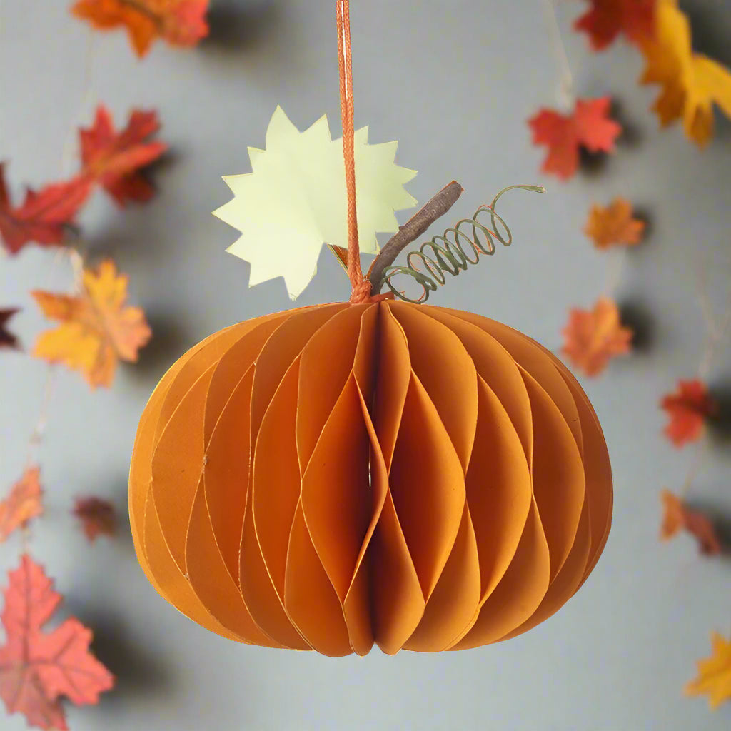 Decorative paper pumpkin with a leaf on autumnal background