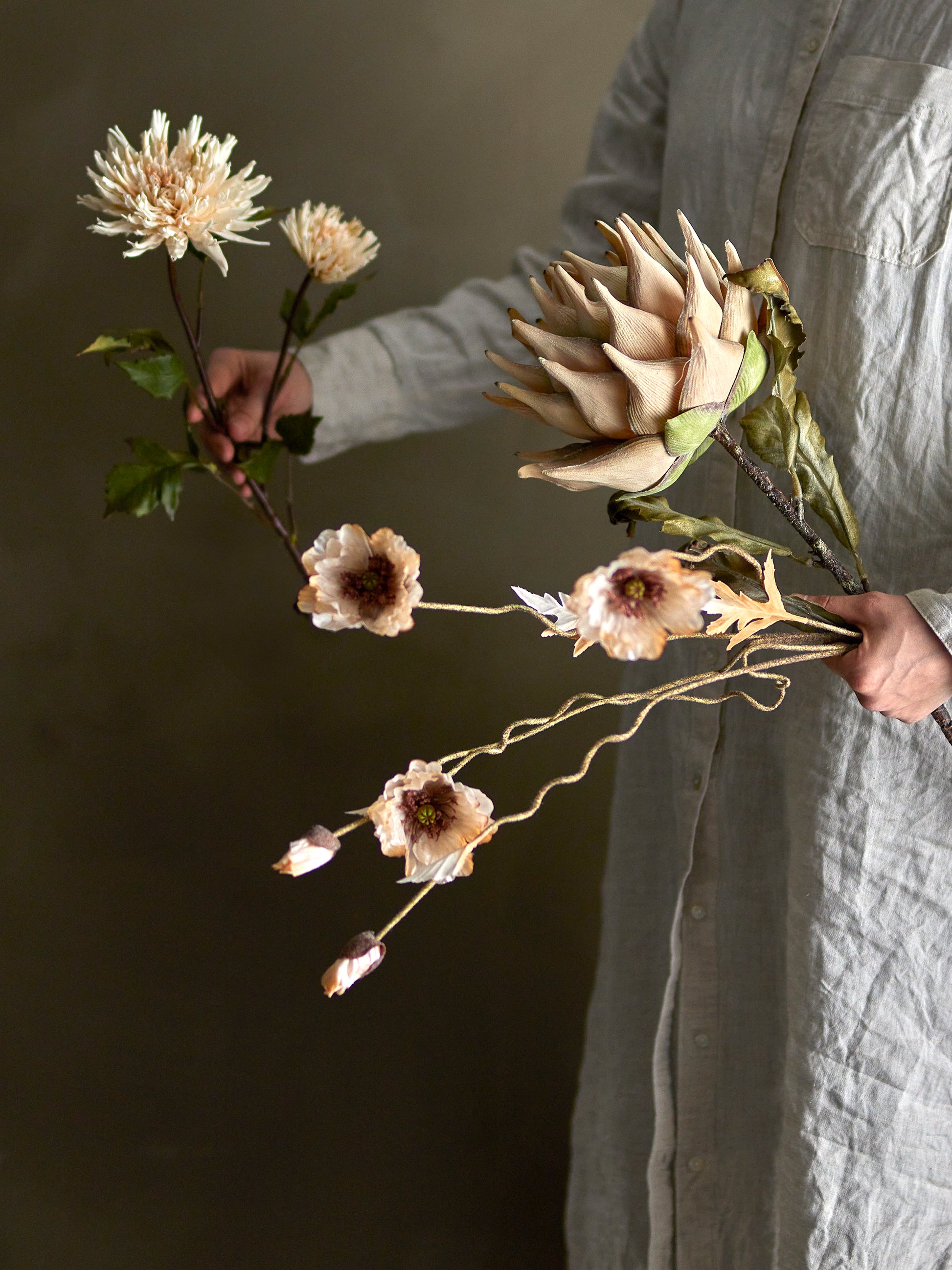 Person holding dried flowers against a dark background