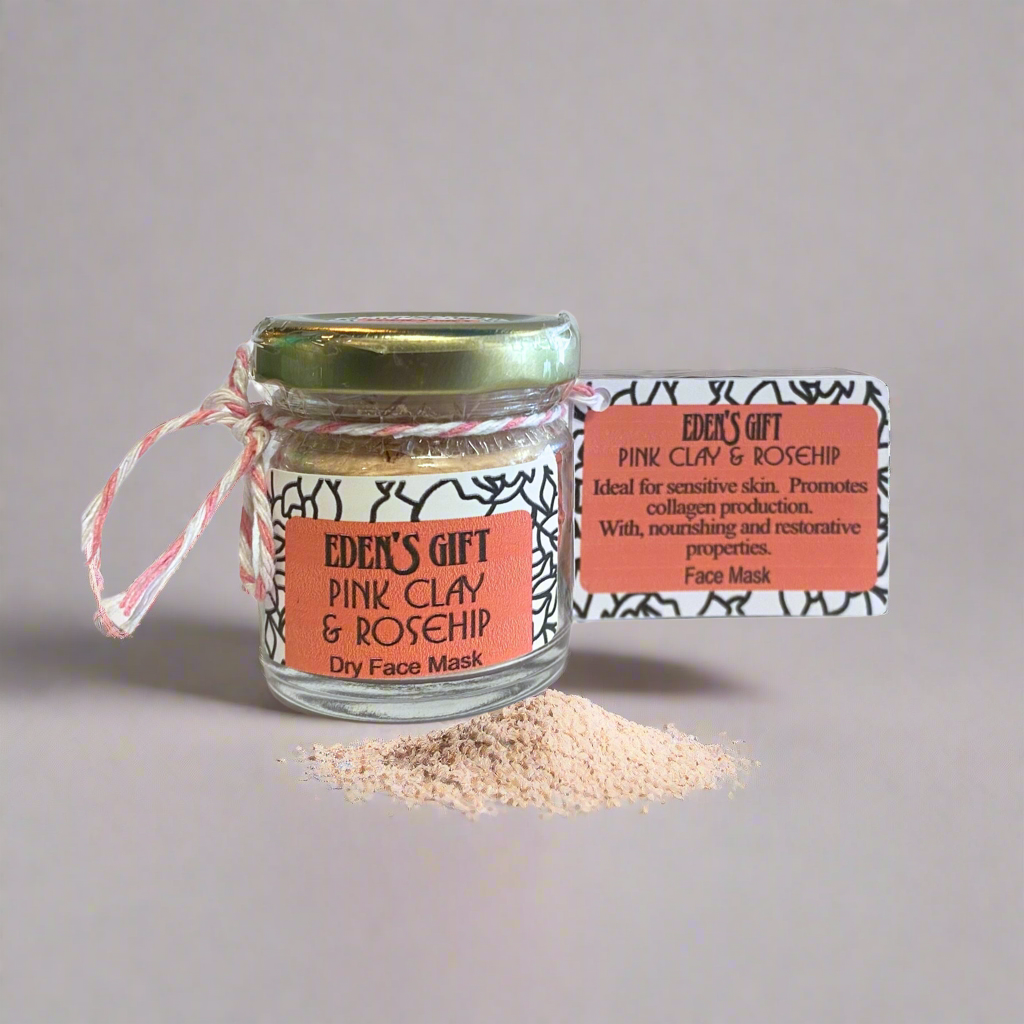 Glass jar of pink clay and rosehip dry face mask with a label on a gray background