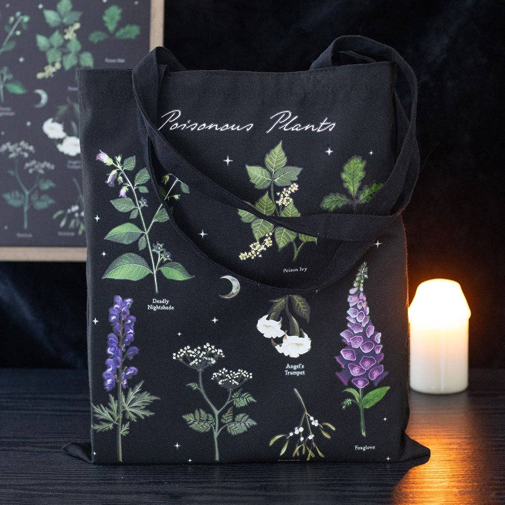 Black tote bag with botanical designs of poisonous plants on a dark background.