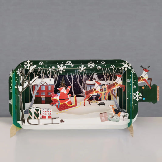 Pop-up Christmas card with Santa sleigh, reindeer, snowy town, and presents, festive 3D card for UK Christmas gifting.
