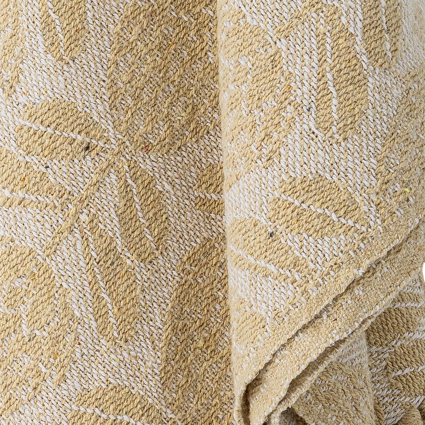 Cream blanket draped over a textured chair with a decorative fan on the wall.