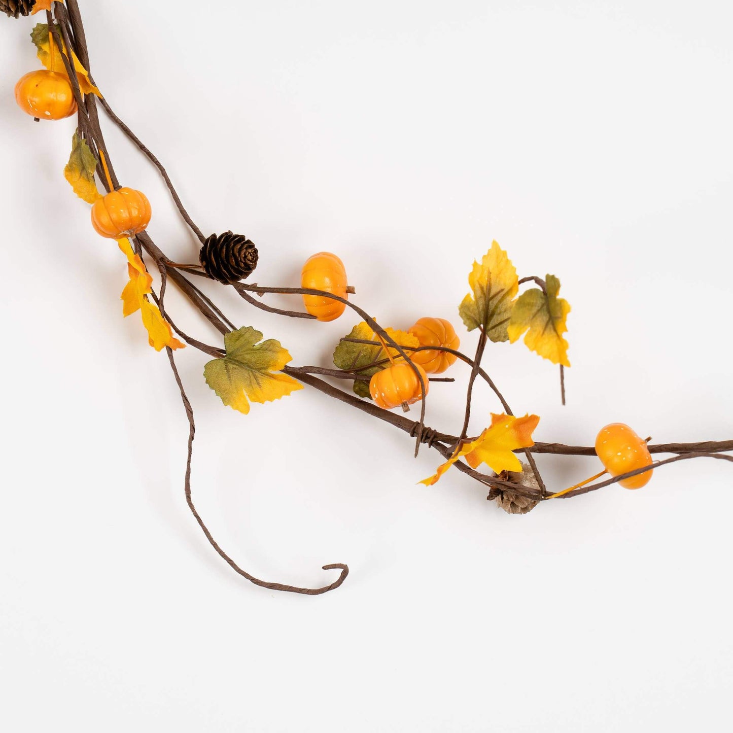 An autumn-themed garland featuring brown vine branches decorated with orange berries, yellow and green leaves, and a small pinecone, laid out diagonally on a plain white background.