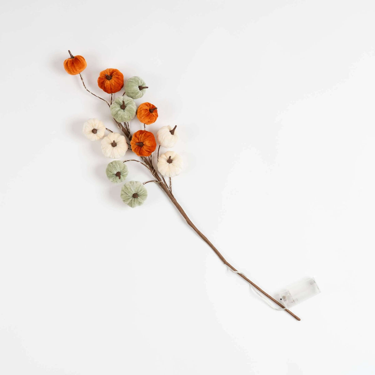 A decorative autumn branch with faux pumpkins and cotton bolls on a thin brown stem, photographed on a clean white background.