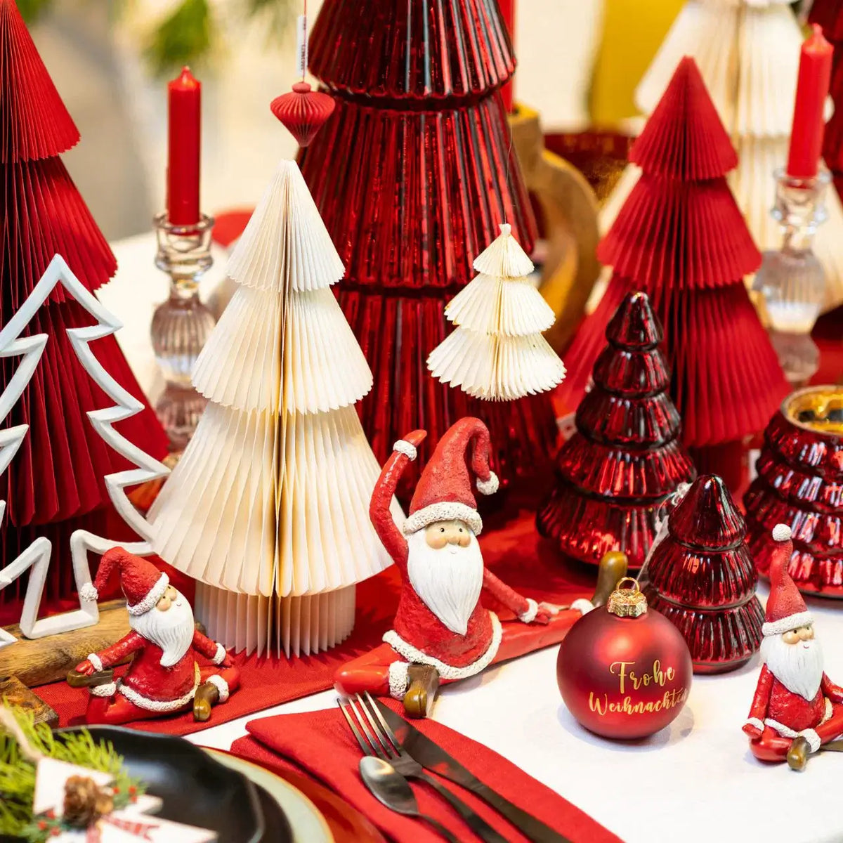 Decorative Christmas table setting with red and white trees, Santa figures, and ornaments.